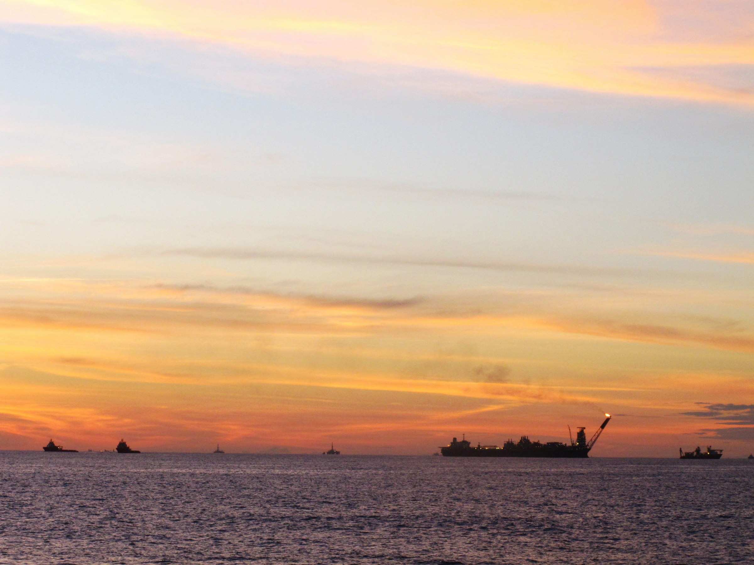 Plataforma de petróleo no horizonte da Bacia de Campos, ao pôr do sol